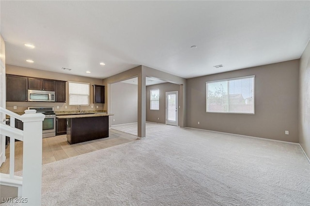7534 Earnshaw Ave, Las Vegas, NV 89179 - kitchen featuring stainless steel appliances, a kitchen island, open floor plan, light carpet, and dark brown cabinets