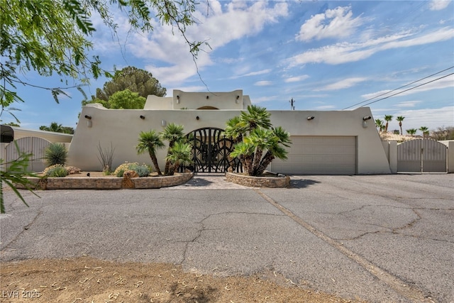 7045 Edna Ave, Las Vegas, NV 89117 - pueblo-style house with a gate, stucco siding, a garage, and asphalt driveway
