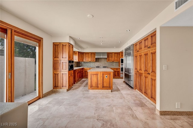7045 Edna Ave, Las Vegas, NV 89117 - kitchen with light countertops, brown cabinets, a kitchen island, built in refrigerator, and tasteful backsplash