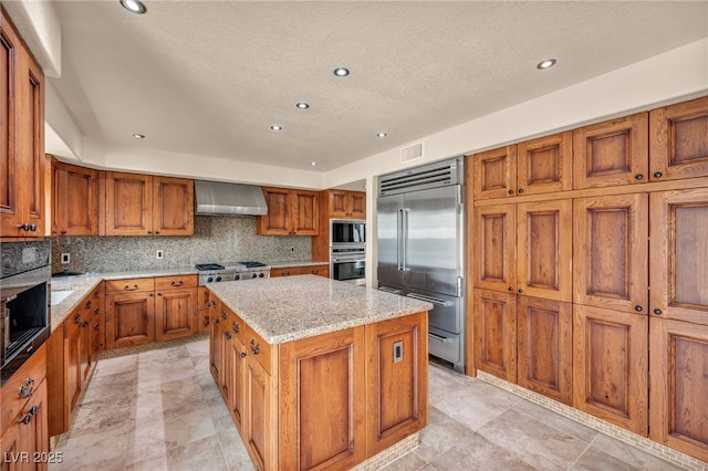 7045 Edna Ave, Las Vegas, NV 89117 - kitchen featuring built in appliances, wall chimney exhaust hood, brown cabinets, a center island, and recessed lighting