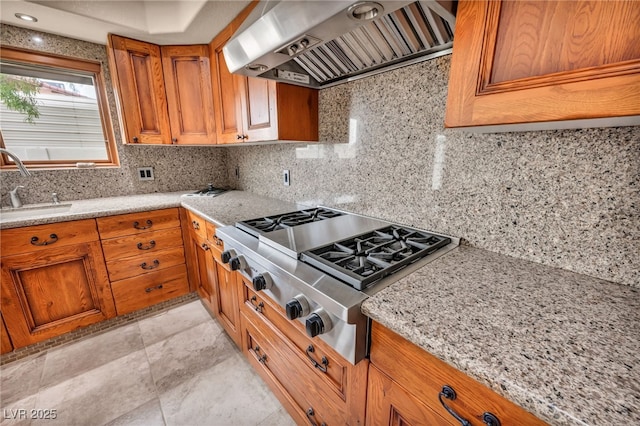 7045 Edna Ave, Las Vegas, NV 89117 - kitchen with extractor fan, stainless steel gas cooktop, brown cabinets, and decorative backsplash