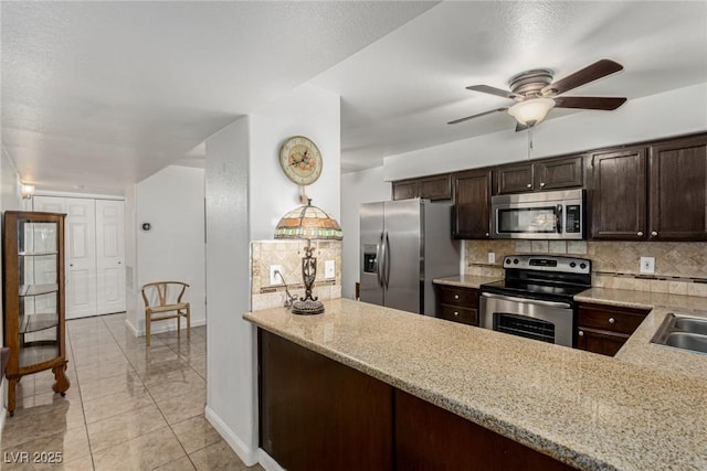 2725 S Nellis Blvd Unit 1037, Las Vegas, NV 89121 - kitchen featuring appliances with stainless steel finishes, decorative backsplash, dark brown cabinetry, a ceiling fan, and light stone countertops