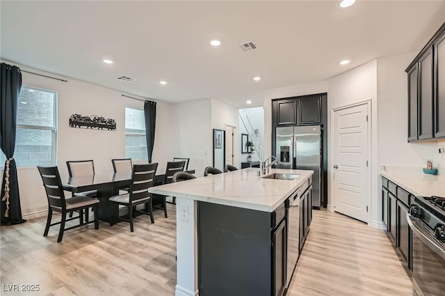 2821 Gaffer Film St, Las Vegas, NV 89156 - kitchen with light wood finished floors, an island with sink, stainless steel fridge, recessed lighting, and range with gas stovetop