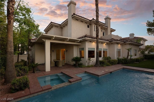 8712 Mesa Canogo Dr, Las Vegas, NV 89148 - back of house with stucco siding, a chimney, a patio, a tiled roof, and a pool with connected hot tub