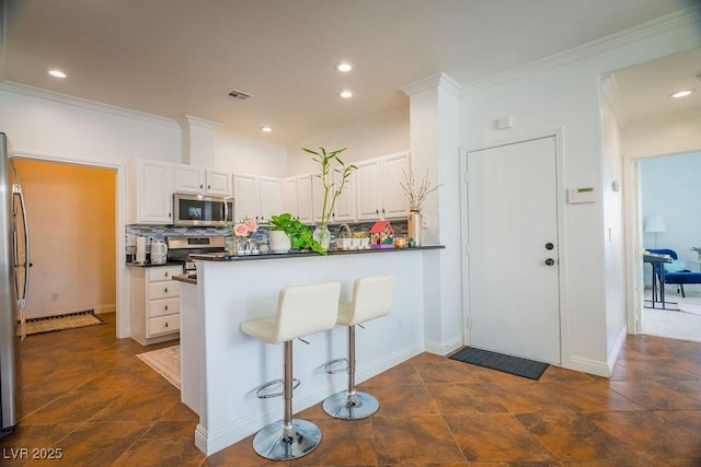 2251 Vangogh Dr, Henderson, NV 89074 - kitchen featuring appliances with stainless steel finishes, backsplash, white cabinets, a peninsula, and dark countertops