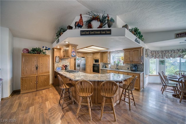 2910 Sunset St, Pahrump, NV 89060 - kitchen featuring appliances with stainless steel finishes, decorative backsplash, a peninsula, light wood-type flooring, and a textured ceiling