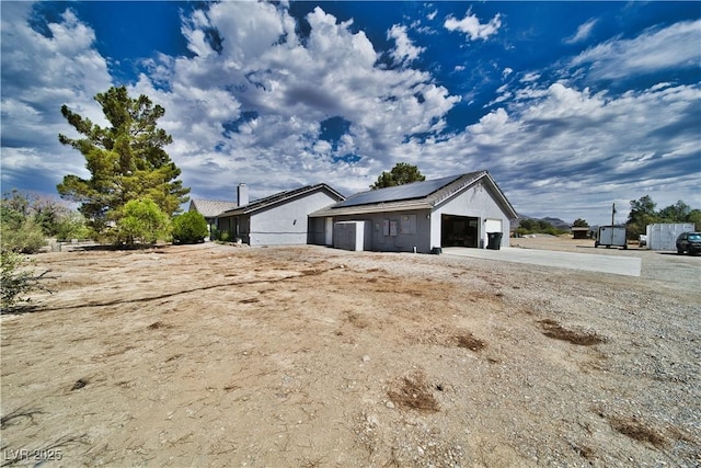 2910 Sunset St, Pahrump, NV 89060 - view of side of property featuring roof mounted solar panels, a detached garage, and stucco siding