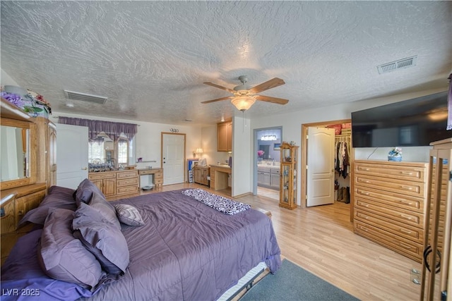 2910 Sunset St, Pahrump, NV 89060 - bedroom featuring a textured ceiling, a walk in closet, light wood-type flooring, ensuite bathroom, and a closet