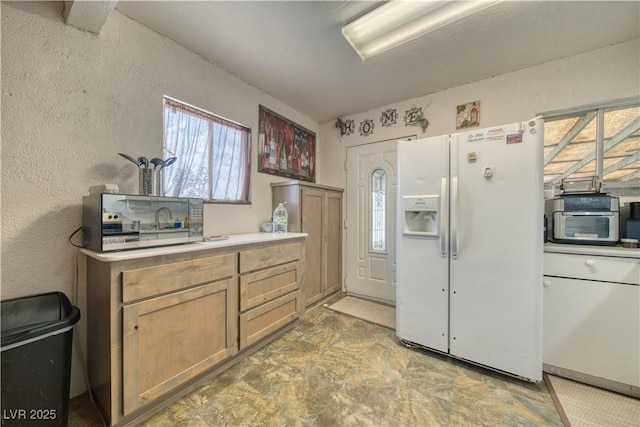 2910 Sunset St, Pahrump, NV 89060 - kitchen featuring white fridge with ice dispenser, light countertops, stone finish flooring, and a textured wall