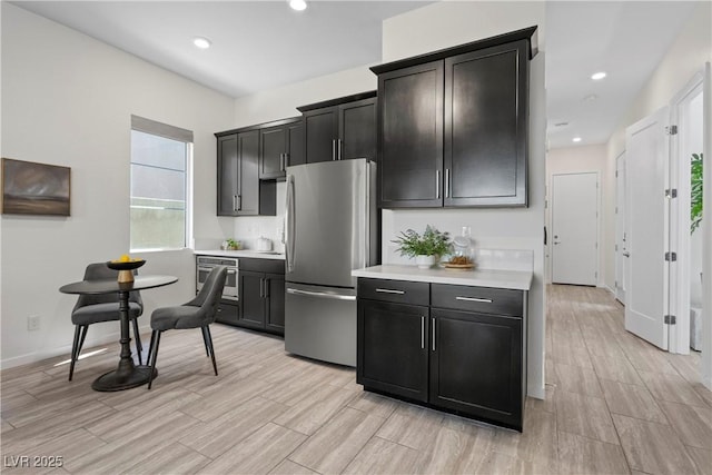 6234 Amber View St, Las Vegas, NV 89135 - kitchen with freestanding refrigerator, light countertops, light wood-style flooring, recessed lighting, and dark cabinetry