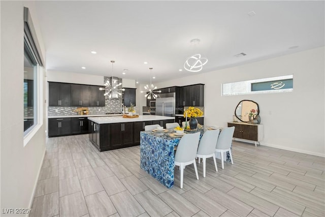 6234 Amber View St, Las Vegas, NV 89135 - kitchen with a chandelier, wall chimney range hood, light countertops, decorative backsplash, and a spacious island