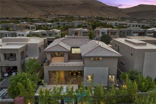 6234 Amber View St, Las Vegas, NV 89135 - back of house at dusk with a mountain view, stucco siding, a residential view, a balcony, and a tiled roof