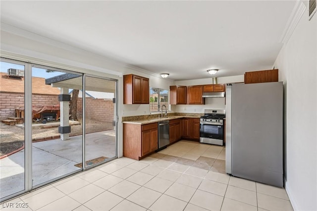 7000 Paddington Way, Las Vegas, NV 89147 - kitchen featuring appliances with stainless steel finishes, brown cabinetry, under cabinet range hood, ornamental molding, and light tile patterned floors