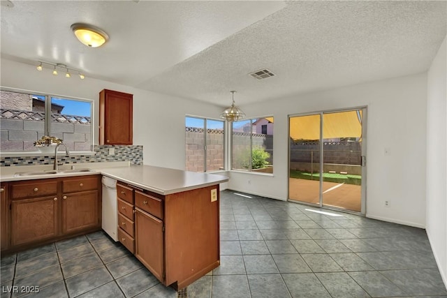 1676 Divinity St, Las Vegas, NV 89142 - kitchen featuring a peninsula, white dishwasher, backsplash, a chandelier, and light countertops