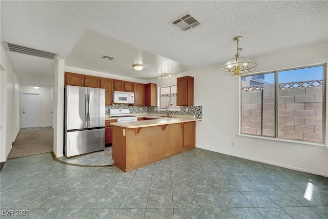 1676 Divinity St, Las Vegas, NV 89142 - kitchen with white appliances, a peninsula, a chandelier, light countertops, and pendant lighting
