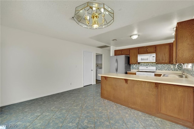 1676 Divinity St, Las Vegas, NV 89142 - kitchen with freestanding refrigerator, range, white microwave, light countertops, and a chandelier