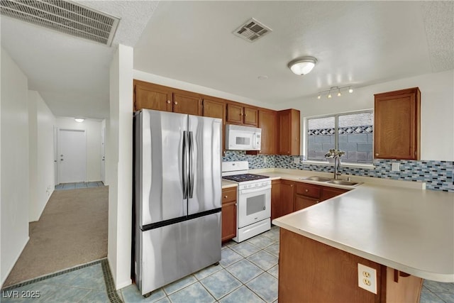 1676 Divinity St, Las Vegas, NV 89142 - kitchen featuring white appliances, light countertops, tasteful backsplash, a peninsula, and brown cabinetry