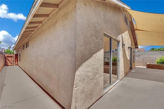 1676 Divinity St, Las Vegas, NV 89142 - view of side of home with a patio, stucco siding, and a gate