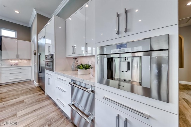 22 Starbrook Dr, Henderson, NV 89052 - kitchen featuring modern cabinets, crown molding, oven, white cabinetry, and tasteful backsplash