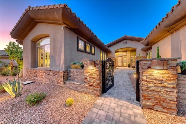 22 Starbrook Dr, Henderson, NV 89052 - view of front of home featuring stucco siding, a gate, stone siding, and a tile roof