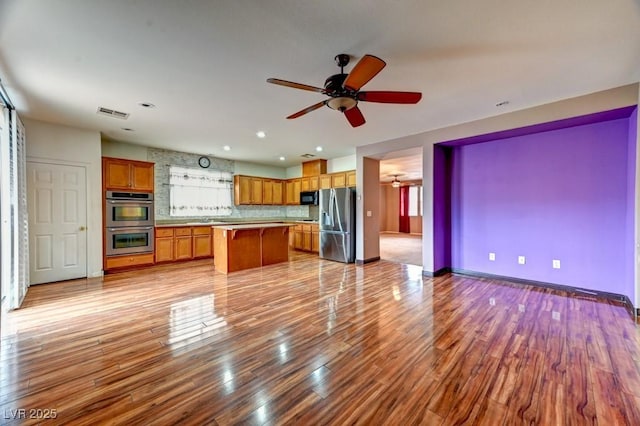 6720 Sand Swallow St, North Las Vegas, NV 89084 - kitchen with appliances with stainless steel finishes, brown cabinets, ceiling fan, a kitchen island, and open floor plan