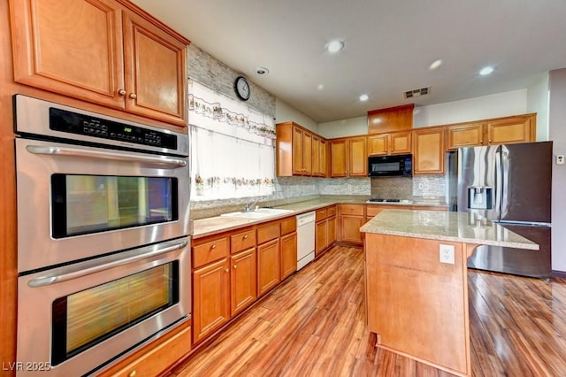6720 Sand Swallow St, North Las Vegas, NV 89084 - kitchen with appliances with stainless steel finishes, light wood finished floors, tasteful backsplash, light stone countertops, and a center island