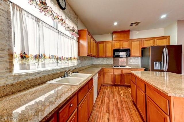 6720 Sand Swallow St, North Las Vegas, NV 89084 - kitchen with stainless steel refrigerator with ice dispenser, black microwave, light wood-type flooring, decorative backsplash, and brown cabinetry