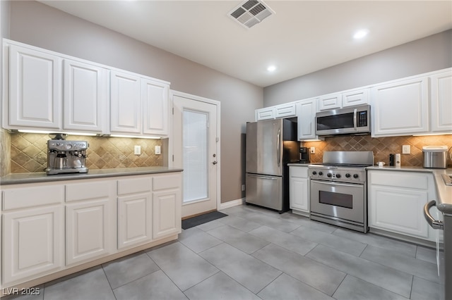 1641 Dark Wolf Ave, Las Vegas, NV 89123 - kitchen with stainless steel appliances, decorative backsplash, white cabinetry, light tile patterned flooring, and recessed lighting