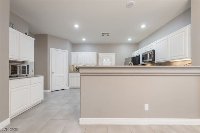 1641 Dark Wolf Ave, Las Vegas, NV 89123 - kitchen with freestanding refrigerator, stainless steel microwave, white cabinetry, recessed lighting, and light tile patterned flooring