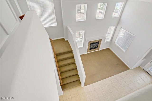 10015 Willowbrook Pond Rd, Las Vegas, NV 89148 - stairway featuring carpet flooring, a glass covered fireplace, and a high ceiling