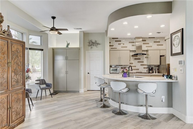 2832 Castle Bar Dr, Las Vegas, NV 89134 - kitchen with wall chimney exhaust hood, tasteful backsplash, a peninsula, ceiling fan, and light countertops