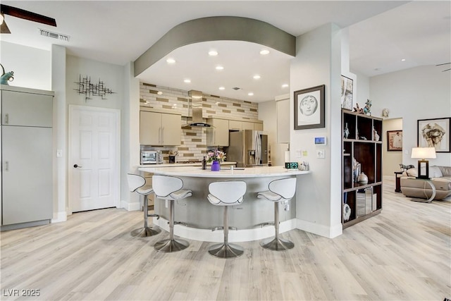 2832 Castle Bar Dr, Las Vegas, NV 89134 - kitchen featuring stainless steel refrigerator with ice dispenser, range hood, light countertops, light wood-style flooring, and a kitchen breakfast bar