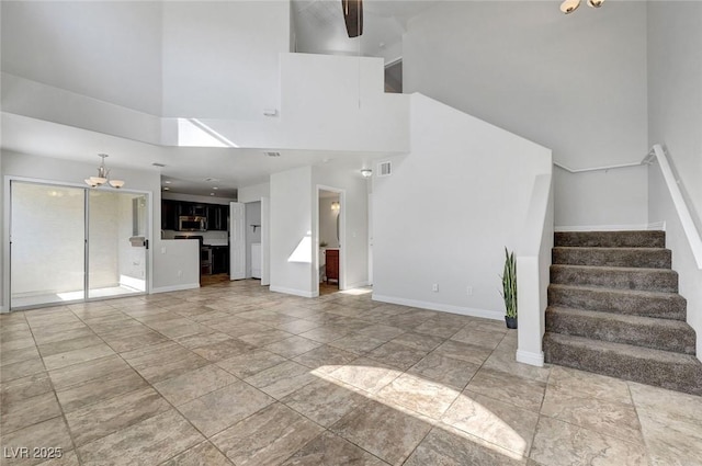 917 Intrigue Way, Las Vegas, NV 89128 - unfurnished living room with a high ceiling, stairway, and a chandelier