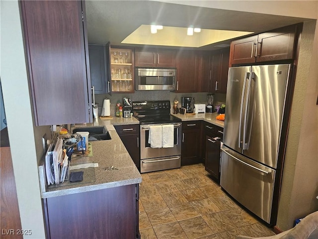 1341 Del Mar St Unit 101, Las Vegas, NV 89119 - kitchen with stainless steel appliances, a raised ceiling, light stone countertops, glass insert cabinets, and dark brown cabinets