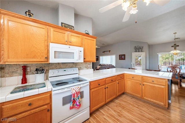 200 E Domingo St, Pahrump, NV 89048 - kitchen with white appliances, tile counters, a peninsula, tasteful backsplash, and vaulted ceiling