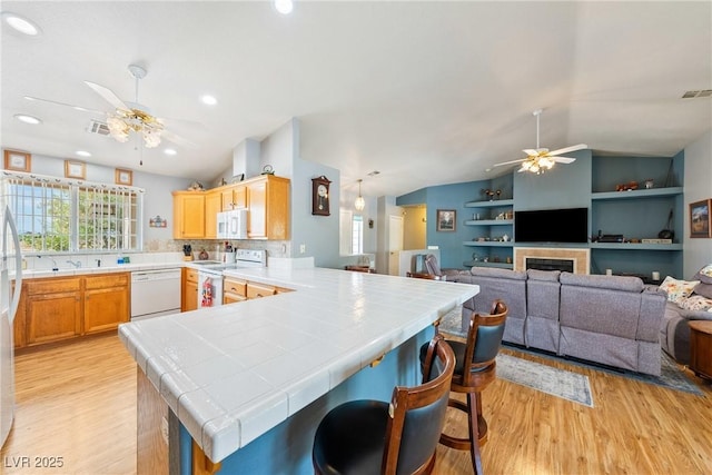 200 E Domingo St, Pahrump, NV 89048 - kitchen featuring white appliances, a ceiling fan, tile countertops, light wood-style flooring, and vaulted ceiling