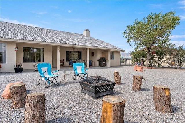 200 E Domingo St, Pahrump, NV 89048 - rear view of property featuring a tile roof, an outdoor fire pit, a chimney, stucco siding, and a patio area