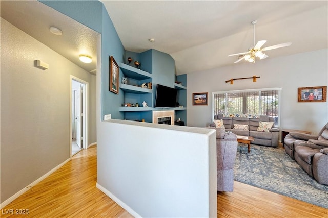 200 E Domingo St, Pahrump, NV 89048 - living room with light wood finished floors, a ceiling fan, a fireplace, built in shelves, and lofted ceiling