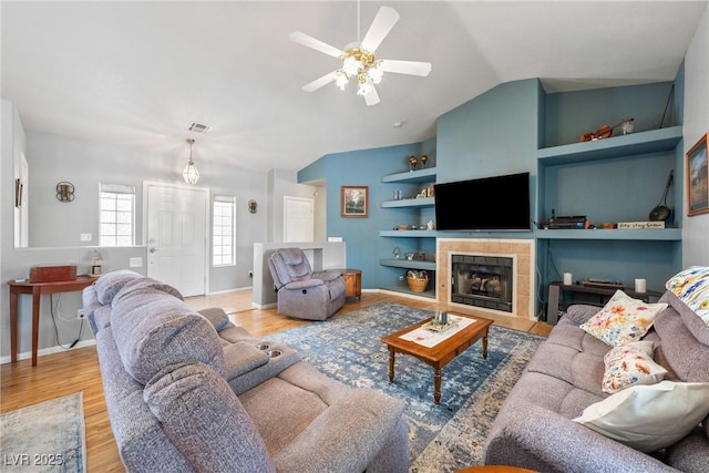 200 E Domingo St, Pahrump, NV 89048 - living room with built in features, lofted ceiling, a ceiling fan, wood finished floors, and a tile fireplace