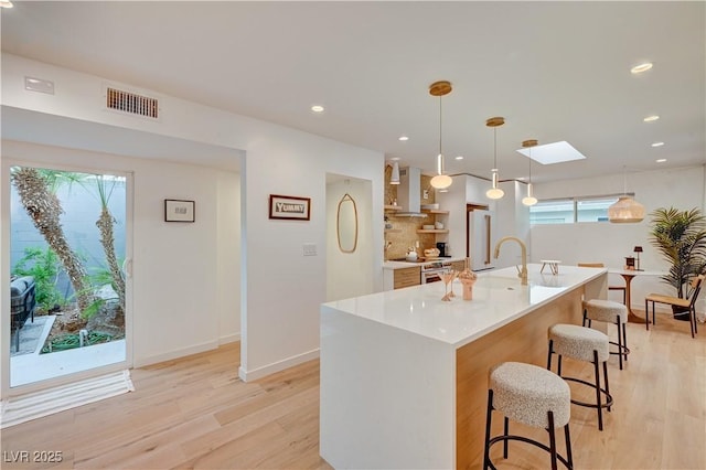 3022 El Camino Ave, Las Vegas, NV 89102 - kitchen featuring light wood finished floors, stainless steel electric range oven, light countertops, a kitchen breakfast bar, and a kitchen island with sink