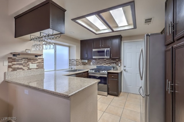 4006 Clove Tree Ct, North Las Vegas, NV 89031 - kitchen with appliances with stainless steel finishes, decorative backsplash, a peninsula, dark brown cabinetry, and light tile patterned floors