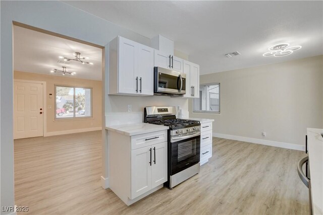 4512 Mark Ave, Las Vegas, NV 89108 - kitchen featuring appliances with stainless steel finishes, light wood finished floors, white cabinetry, a chandelier, and light stone counters