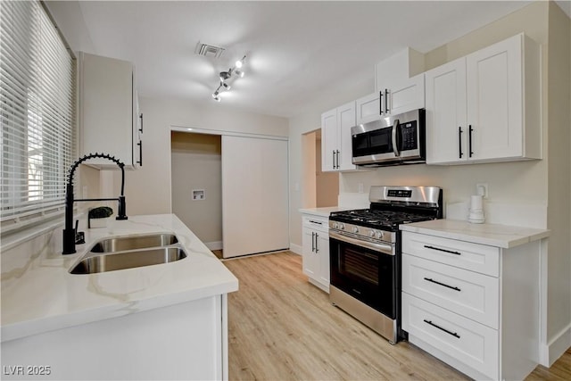 4512 Mark Ave, Las Vegas, NV 89108 - kitchen featuring stainless steel appliances, light wood-style flooring, light stone countertops, and white cabinets