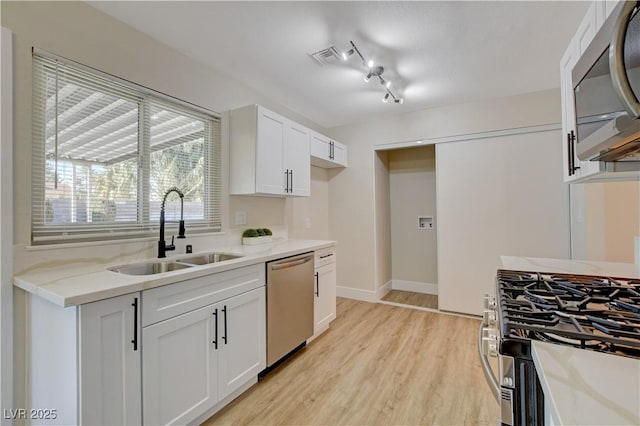 4512 Mark Ave, Las Vegas, NV 89108 - kitchen with stainless steel appliances, light wood finished floors, white cabinets, and light stone counters