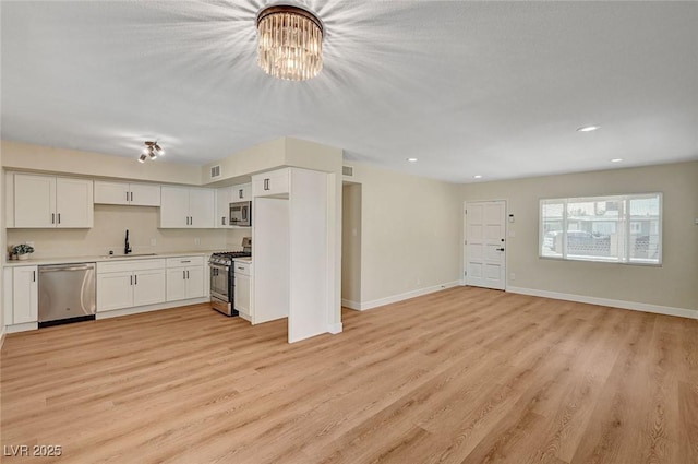 4804 Apawana Ln, Las Vegas, NV 89108 - kitchen with stainless steel appliances, white cabinets, light wood-style flooring, open floor plan, and recessed lighting