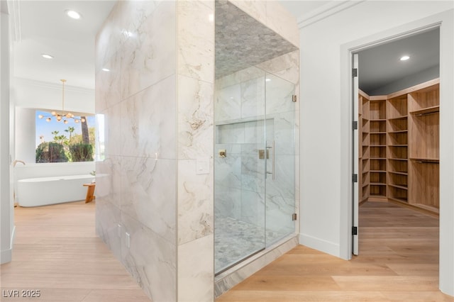 8617 Titleist Cir, Las Vegas, NV 89117 - full bathroom featuring a marble finish shower, a chandelier, a freestanding tub, a spacious closet, and wood finished floors