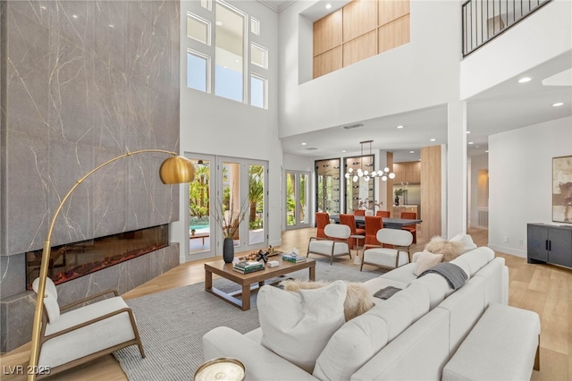 8617 Titleist Cir, Las Vegas, NV 89117 - living area featuring light wood-type flooring, a towering ceiling, a fireplace, recessed lighting, and a chandelier