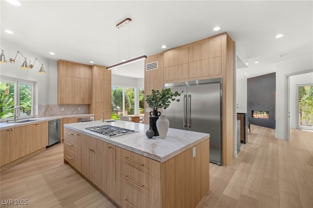 8617 Titleist Cir, Las Vegas, NV 89117 - kitchen with appliances with stainless steel finishes, modern cabinets, light brown cabinets, a kitchen island, and recessed lighting
