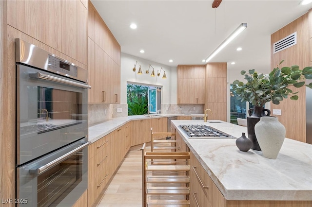 8617 Titleist Cir, Las Vegas, NV 89117 - kitchen with light brown cabinetry, modern cabinets, a center island with sink, appliances with stainless steel finishes, and recessed lighting