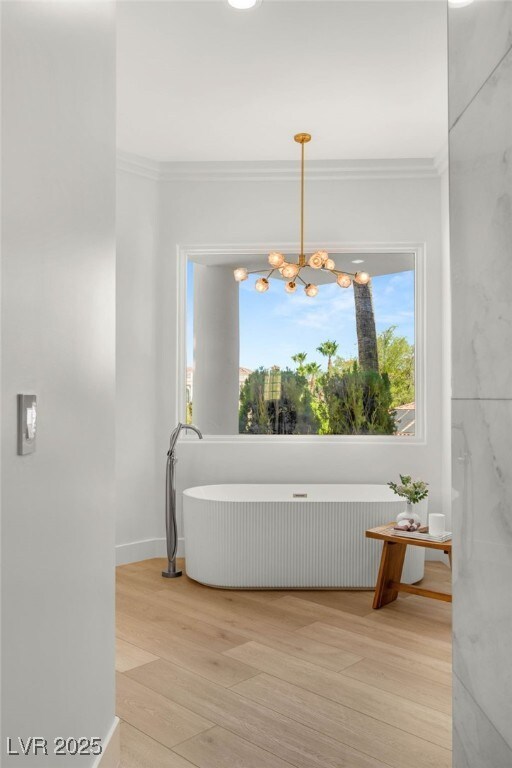 8617 Titleist Cir, Las Vegas, NV 89117 - bathroom featuring wood finished floors, plenty of natural light, ornamental molding, radiator, and a chandelier
